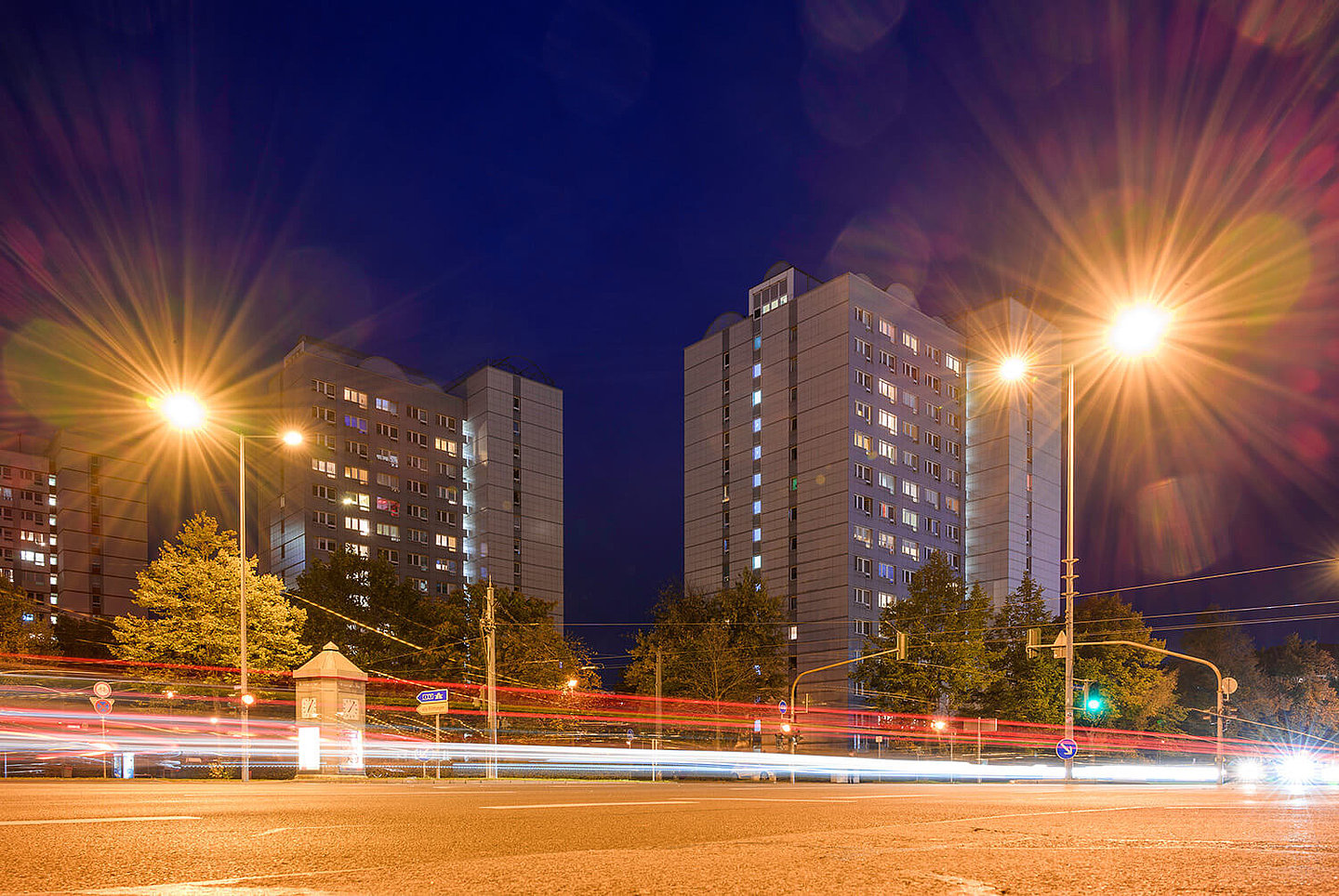 A busy street at night, behind which are blocks of flats
