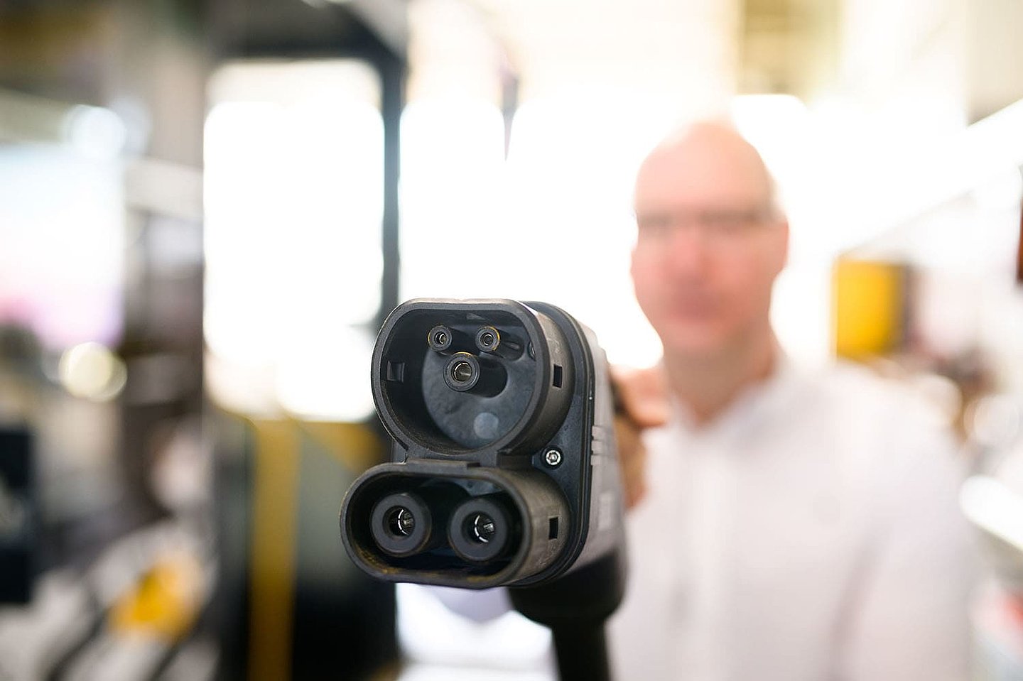 Ein Mann hält das Ladekabel seines Busses in die Kamera