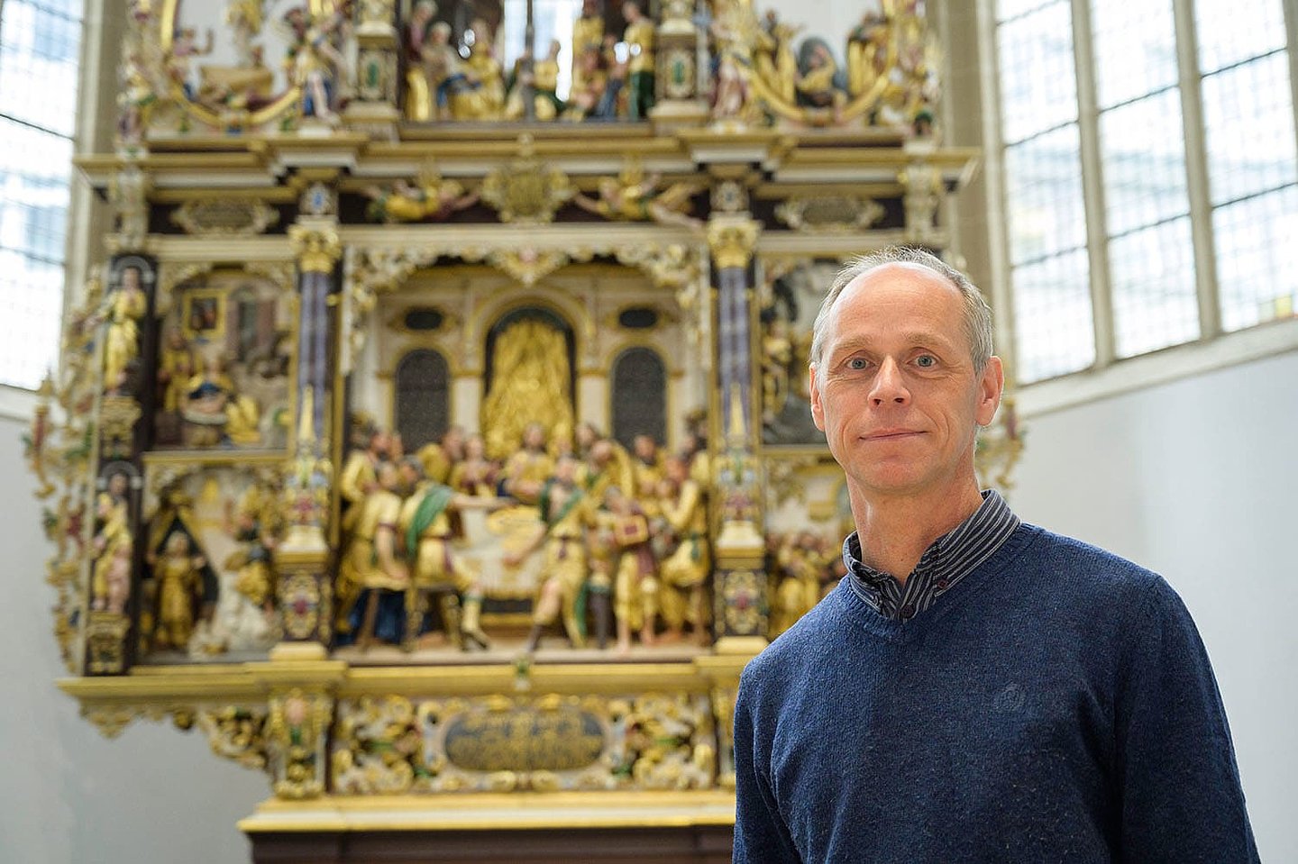 Ein vor dem Altar stehender Mann sieht gerade in die Kamera