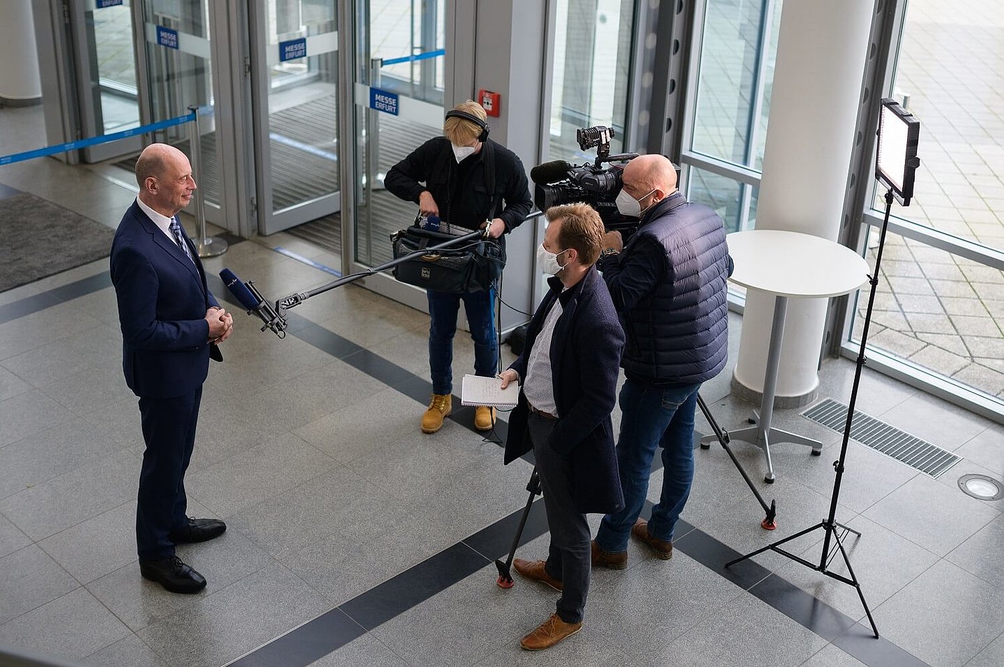 Wolfgang Tiefensee mit Kamerateam und Direktor aus der Vogelperspektive vor dem Eingang der Messe Erfurt auf der EFRE Jahresveranstaltung 2020